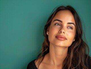 Pretty brazilian woman with sensual facial features looks in front of her on a solid color background, half body photo, space for text