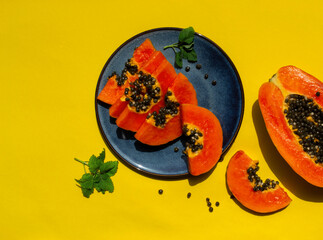 Sliced papaya fresh fruit  in blue plate n the yellow background flat lay