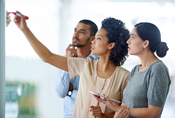 Business people, writing and thinking with glass board for schedule planning, tasks or agenda at office. Group of creative employees taking notes for discussion, brainstorming or startup at workplace