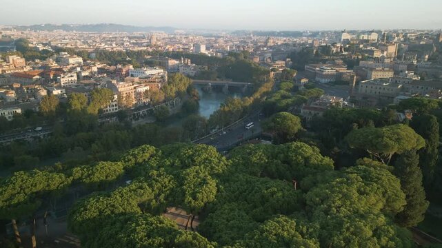 Drone flies above fluffy green trees to reveal river and roadway in Orange Garden Rome Italy