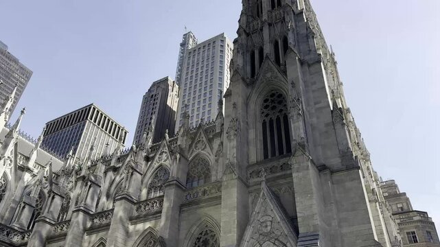 A close-up view of the intricate Gothic architecture of St. Patrick's Cathedral, set against the backdrop of modern skyscrapers in Midtown Manhattan, New York City.