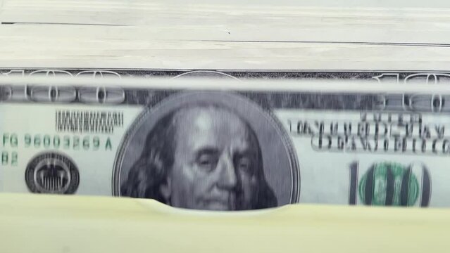 Wad of money, 100 bills with a portrait of Benjamin Franklin shrinking in the money counter, close-up