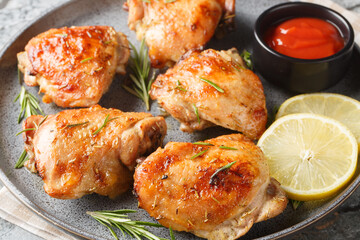 Delicious homemade Lemon rosemary chicken thighs served with ketchup close-up in a plate on the table. Horizontal