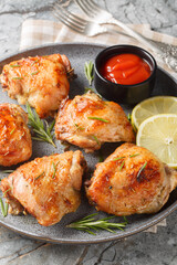 Lemon rosemary chicken thighs served with ketchup close-up in a plate on the table. Vertical