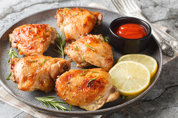 Baked Rosemary Lemon Chicken thighs served with ketchup close-up in a plate on the table. Horizontal
