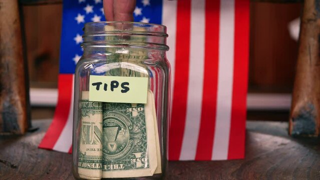Tip jar with dollars and American flag background c