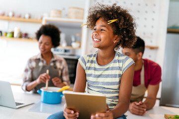 Happy african family having fun with device at home. Black parents and child using digital tablet