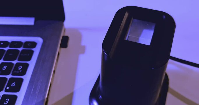 user uses fingerprint reader to access a security system near a notebook pc, concept of security and cyber attacks
