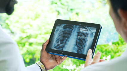 A group of researchers or medical workers in white coats looking at medical data on a tablet