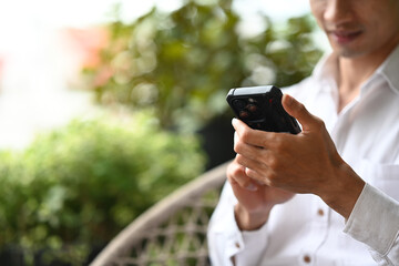 Cropped shot of businessman using mobile phone while sitting at an outdoor cafe