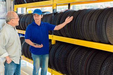 Car tire sales man present suggest recommend tyre products model in car auto garage workshop...