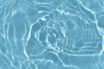 Blue water with ripples on the surface. Defocus blurred transparent blue colored clear calm water surface texture with splashes and bubbles. Water waves with shining pattern texture background.