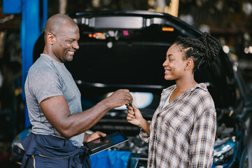 Garage worker return give a car key to customer for vehicle service maintenance check finished complete.