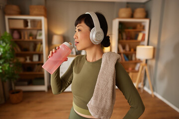 Asian woman drinking water and resting after workout at home
