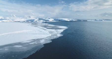 Fly above frozen panorama of Antarctic winter landscape. Aerial drone ice ocean and snow-covered...