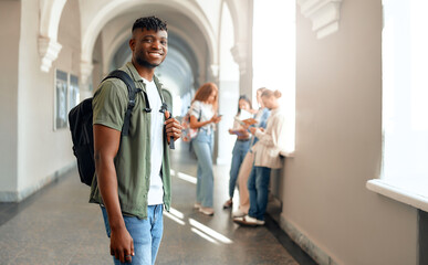 A student with a smile is walking in a university hallway as classmates chat in the background