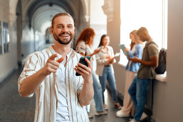 A happy student is seen in a university hallway, smiling while using a smartphone