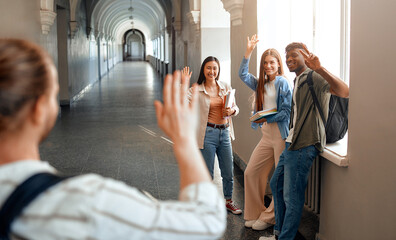Students in university corridor exchanging greetings and creating a joyful atmosphere