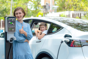 Environmental awareness family with eco-friendly electric car recharging battery from home EV...