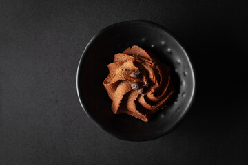  chocolate chip cookie is placed in a black bowl on a black background.