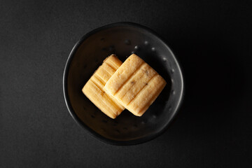 piece of sweet and salted Cumin Cookie or Indian Jeera Cookie, placed in a black bowl on a black background.