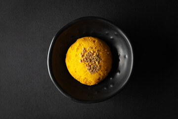 pieces of  Yellow cookies placed in a black bowl on a black background.