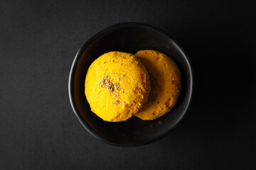 pieces of  Yellow cookies placed in a black bowl on a black background.