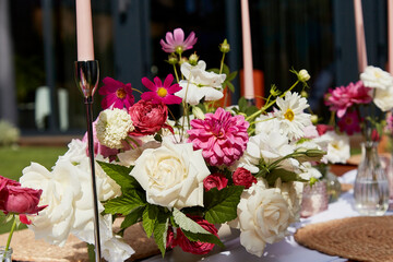 Elegant table setting with pink peonies and roses in festive outdoor picnic. Aesthetic design for summer garden party picnic.