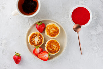 Vegan cheesecakes with berries, sweet sauce, cashew, tofu and cup of tea. Healthy breakfast. Syrniki, cheese pancakes. Sugar, lactose and gluten free. Top view.