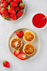 Vegan cheesecakes with berries, sweet sauce, cashew and tofu. Healthy breakfast on a light table. Syrniki, cheese pancakes. Sugar, lactose and gluten free. Vertical orientation, top view.