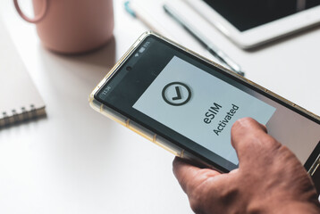 Advantage of eSIM connection for network services concept. A person's mobile phone displaying eSIM activated successfully.