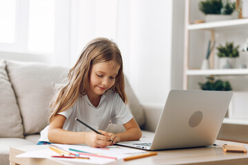 Young girl sitting on couch with laptop and pencil, engaged in online learning or creative work