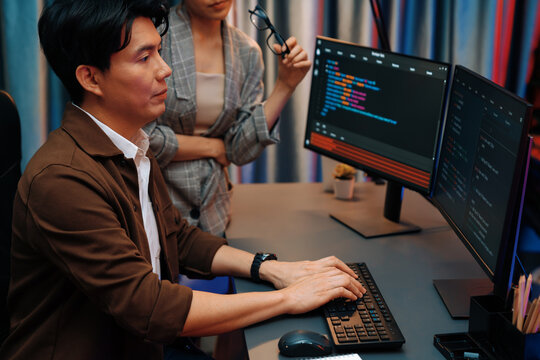 IT developers discussing with point to intelligent website development coder system running data online two screens information technology at neon light room at modern office. Infobahn.