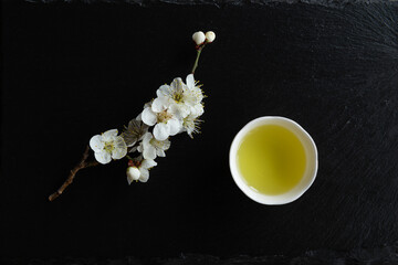 Japanese green tea and flowers on black granite board background. Japan.