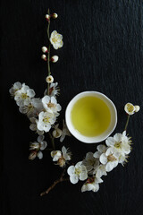 Green tea and Ume flowers on a black granite board background. Japan.