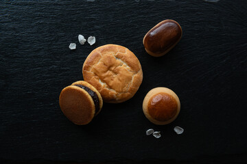 Traditional Japanese sweets, flower petals and Green tea in a beauty minimalist aesthetic arrangement on black granite board background. 
