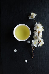 Japanese green tea and Ume (apricot) flowers in a beauty minimalist aesthetic arrangement on black granite board background. Japan.