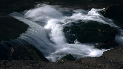 Close-up of fast moving water flowing over smooth stones