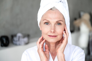 Middle age woman touching skin on face after applying moisturizer cream