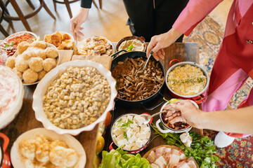 Hands picking up delicious food from buffet assorted on wooden table in restaurant.