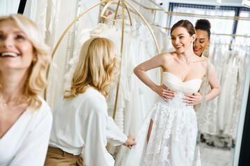Naklejka premium A young, beautiful bride in a white dress stands in front of a mirror, admiring her reflection in a wedding salon.