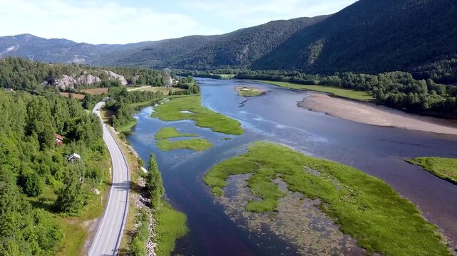 Drone footage showcasing a picturesque Norwegian landscape with lush greenery, a winding river, and surrounding mountains under clear skies.