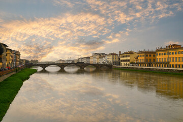 Obraz premium Sunset view of the Arno River running through the city with the Ponte alla Carraia, a five-arched bridge, Florence, Tuscany, Italy