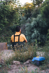 a fisherman sits on the pier and fishes from the shore. Focus on the fishing tackle case