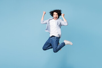 Full body young man he wear shirt white t-shirt casual clothes jump high doing winner gesture celebrate clenching fists say yes isolated on plain pastel light blue cyan background. Lifestyle concept.