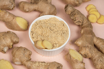 Ground ginger root powder natural spice seasoning on pink background