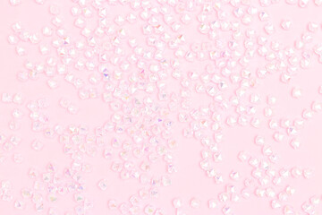 Texture made from iridescent acrylic beads scattered on a pink background.