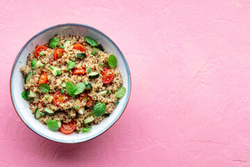 Quinoa tabbouleh salad in a bowl, a healthy dinner with tomatoes and mint, shot from above with copy space
