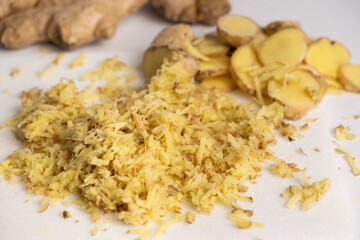 Pieces of finely grated fresh ginger root on kitchen board