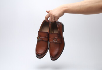 Hand holding pair of modern leather shoes on white background